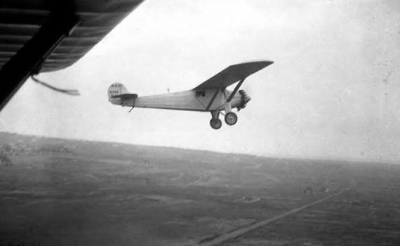 a black and white photograph of a biplane flying