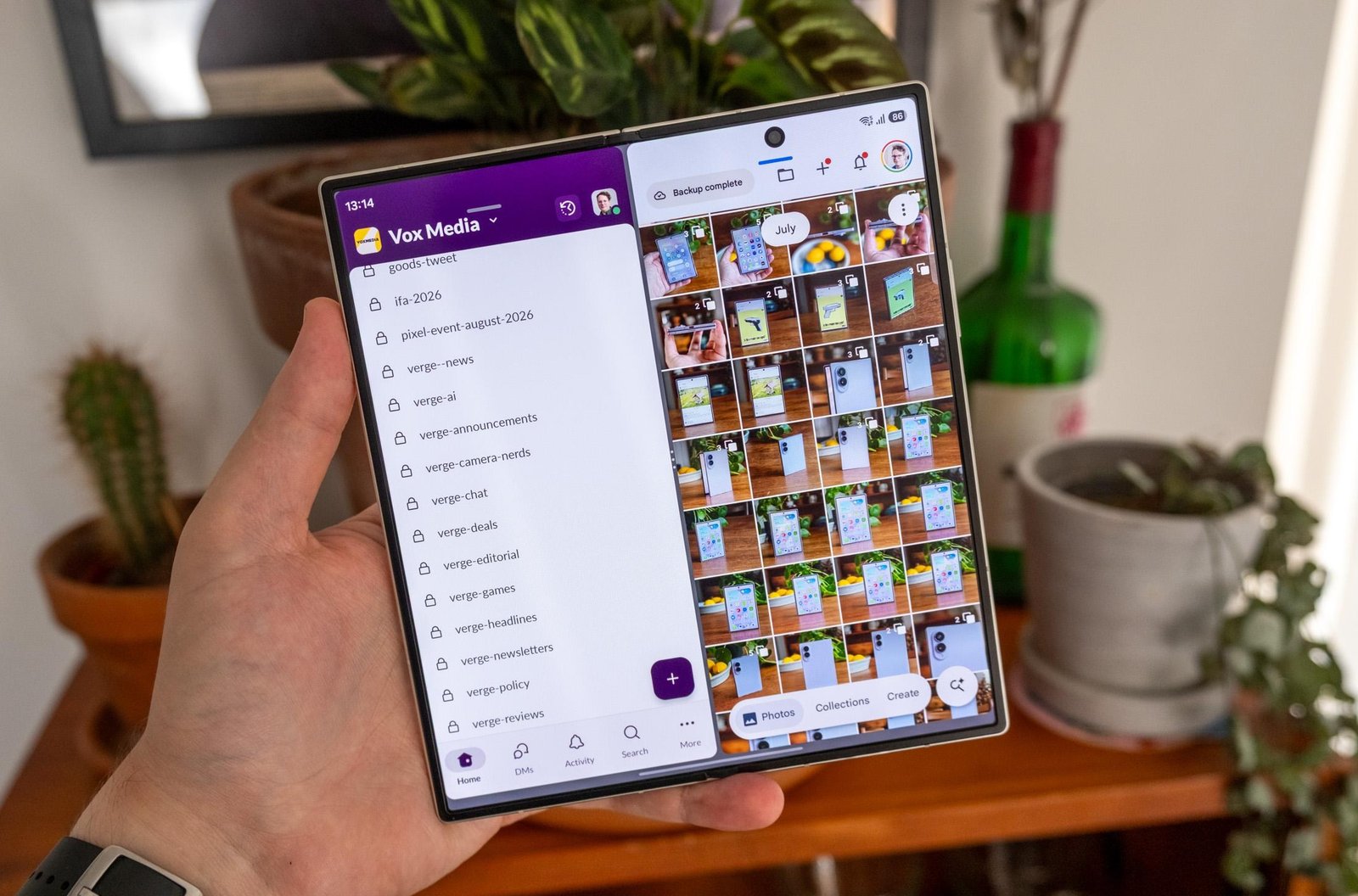 Photo of Samsung Galaxy Z Fold 8 Ultra in a hand in front of a bookcase, showing split-screen multitasking on the inner display