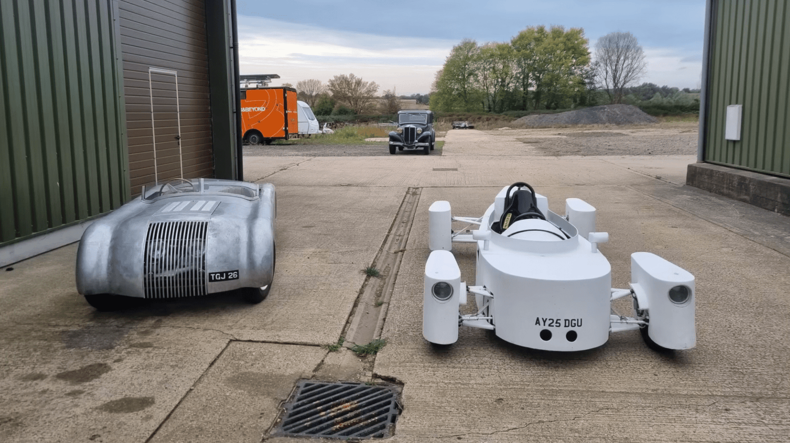 a vintage gray car next to a white DIY sports car 