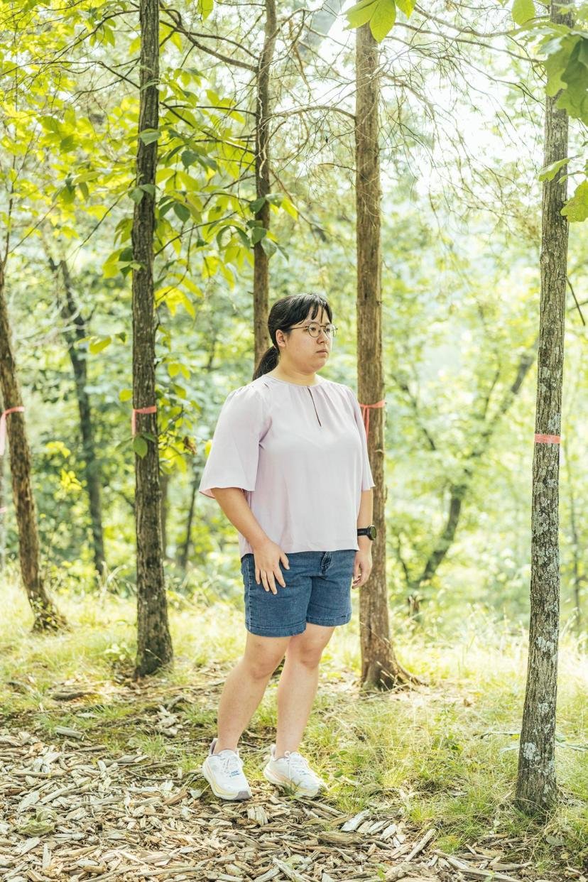 Madison Taggart stands in her backyard among trees marked by pink ribbons to show where a proposed transmission tower would go.