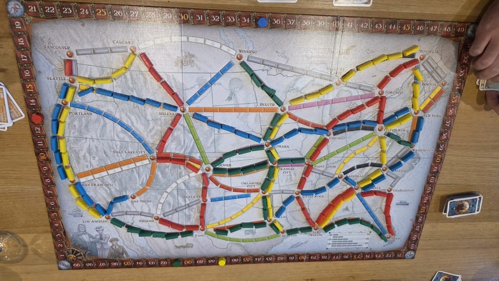 Ticket to ride finished board with various coloured trains on the board and train cards around the edges.
