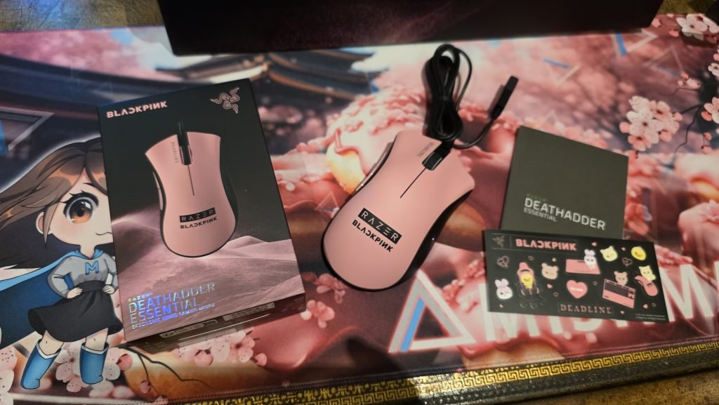 Top down of the mouse unboxing showing the box, mouse with black cable, Quickstart guide, and Razer BlackPINK sticker sheet.