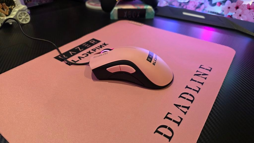 Side shot of the mouse turned on with its pink glow, and sitting on the Razer BLACKPINK mousemat.