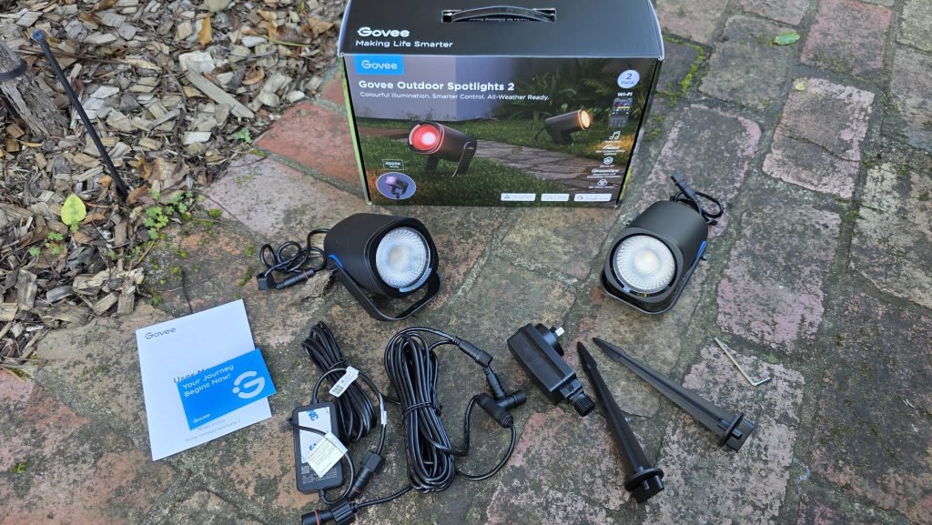 Unboxing showing the two lights, two separate stakes, user manual, Govee Home App flyer, power plug, and cables.