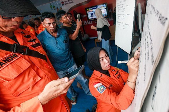 Relatives of passengers look on as a National Search and Rescue Agency (Basarnas) officer writes updates on a whiteboard, amid ongoing rescue operations on the stricken Virgo Transport 8 ferry.