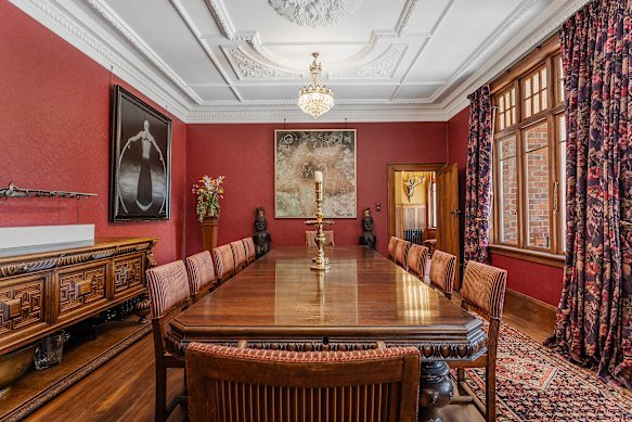 The elegant dining room with oak table,  ornate ceiling and eclectic artworks. 
