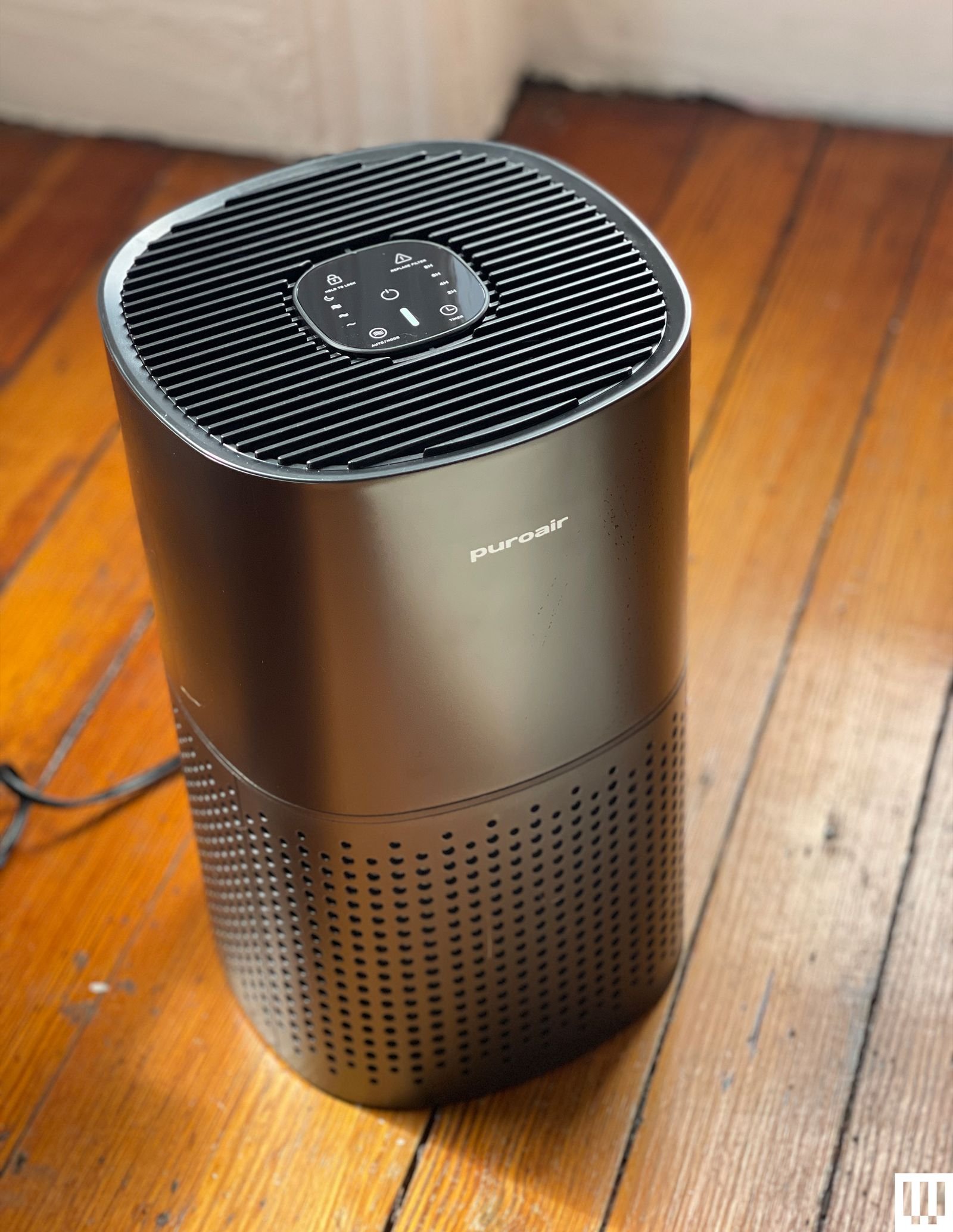 Black air purifier sits on brown wood floor