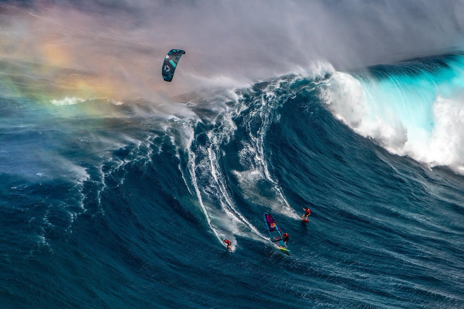 a surfer, windsurfer and kitesurfer sharing the same towering wave