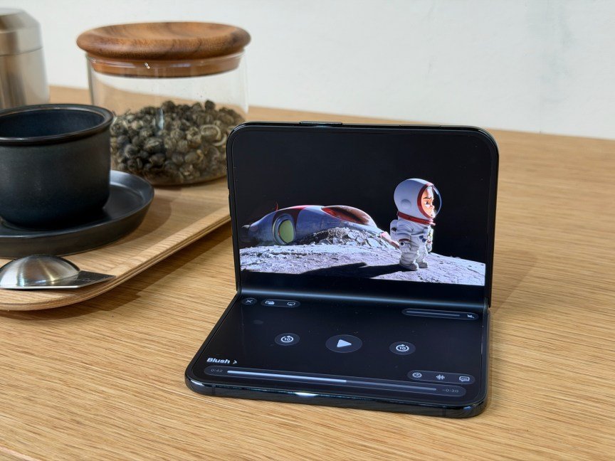 A foldable phone unfolded halfway and resting on its bottom half, with the top showing a video.