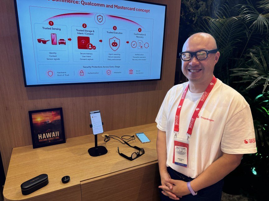 A man wearing smart glasses stands in front of a demo stand with a phone on display.