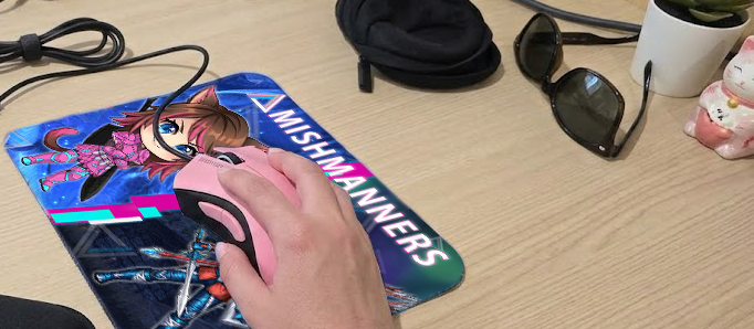 Side shot of my hand on the mouse, sitting at a coworking desk in Singapore. There's the Razer Mouse pouch next to it, sunglasses, and a Chinese cat on the desk.