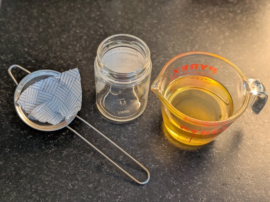 strainer har and measuring cup of oil on table
