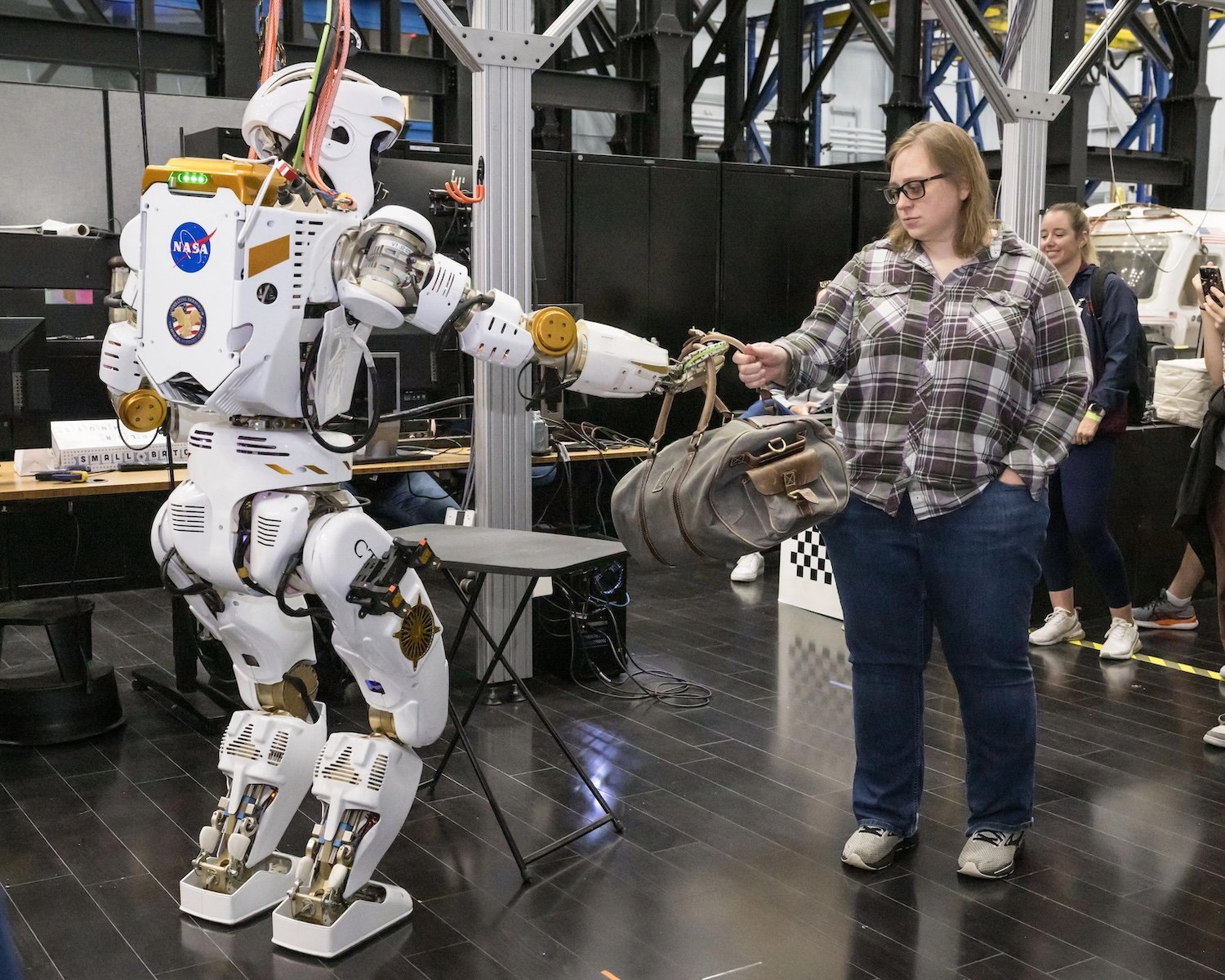 During a demonstration, Valkyrie hands Dexterous Robotics Team member Emma Zemler a packed duffel bag in 2024. Credit: NASA / Helen Arase Varga