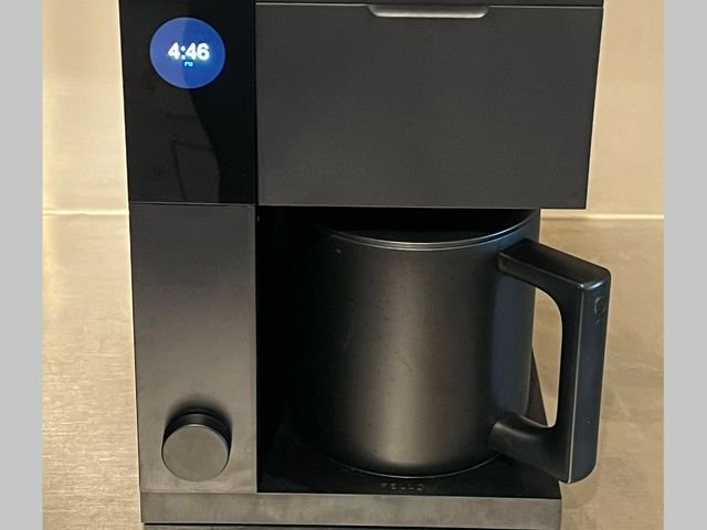 Front view of the Fellow Aiden Precision Coffee Maker, a black, rectangular coffee maker with small digital screen on the left and a large black coffee pot