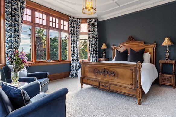 The Spain Suite has a French antique bed, rich blue interiors, bay windows and French doors that open to a balcony with views of Old Man Range.