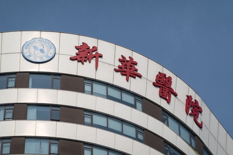 The curved facade of Xinhua Hospital, with Chinese text and the emblem of the hospital visible.