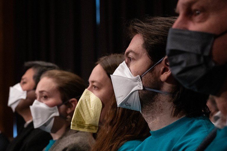A row of people wearing COVID style protective face masks.