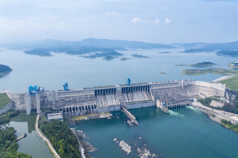 An aerial view of a vast hydroeletric dam dividing two large bodies of water with various islands in the distance.