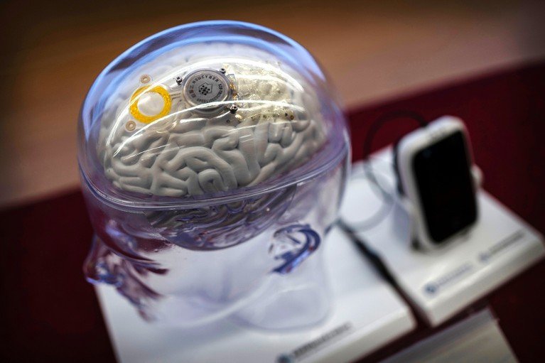 A semi-invasive brain–computer interface system is shown on a model showing a transparent skull and brain.