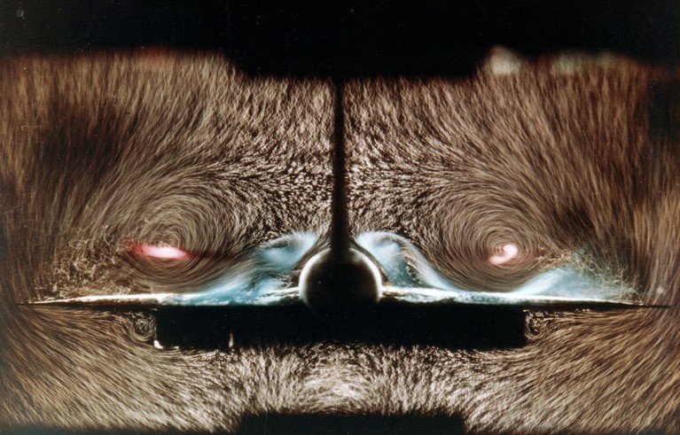 ONERA hydrodynamics-tunnel airflow study, showing a Concorde trailing-edge cross-section and air movement around a central vertical stabiliser and twin engine nacelles. Brown fur tufts reveal swirling flow patterns, with pale blue and pink highlights marking airflow disturbances beside nacelles.