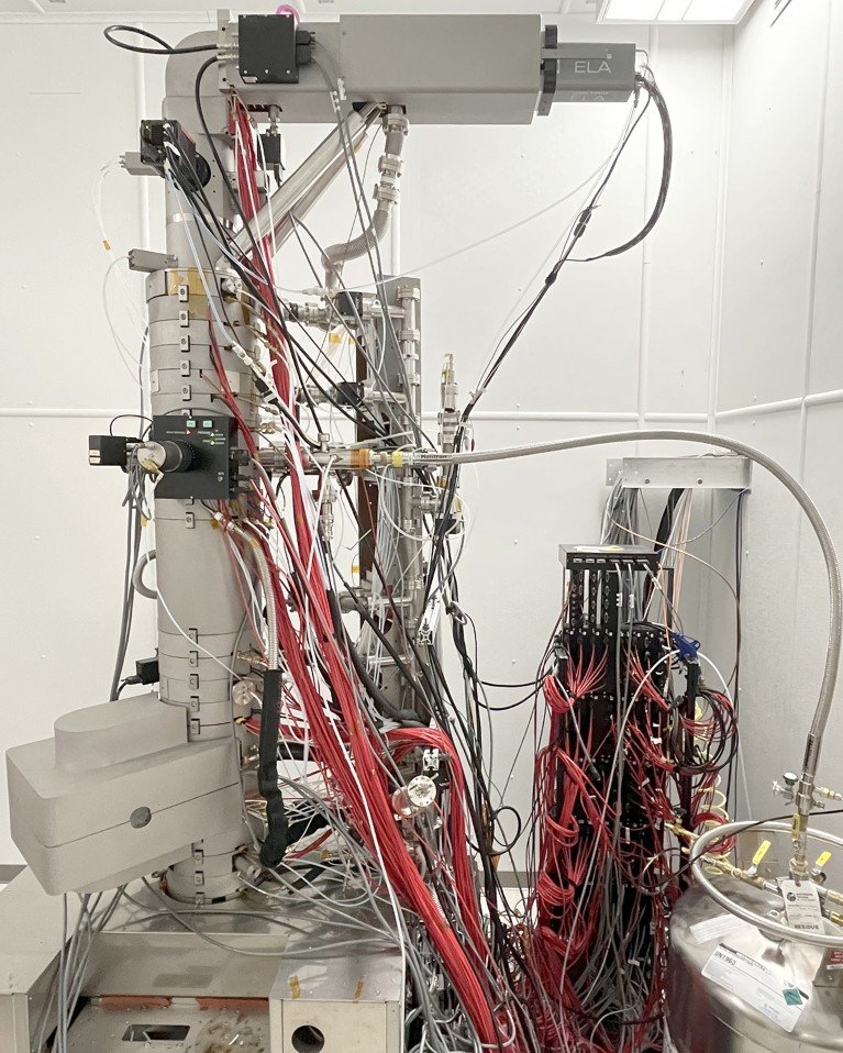 Liquid helium microscope with microscope column, helium dewar, and connecting transfer line.