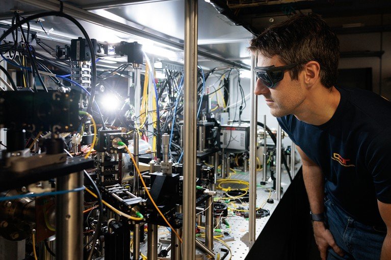 A researcher wearing eye protection looks at the bright glowing light emitted from the lutetium ion clock.