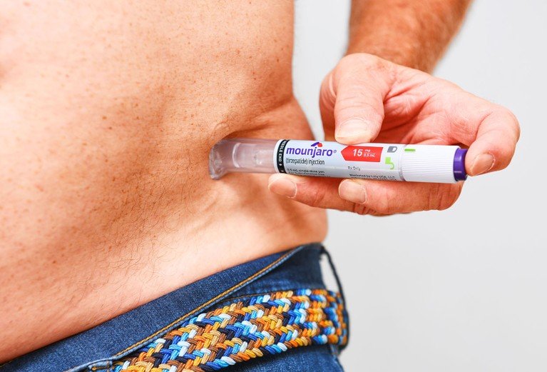 Close up view of a person using an injection pen to administer the Mounjaro weight loss drug to their gut.