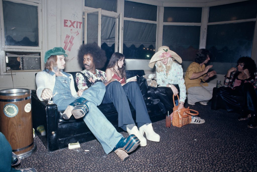Clubbers sitting on a sofa backstage at the Whisky a Go Go, a nightclub on Sunset Boulevard in West Hollywood, California, circa 1975. On the wall behind them, written in red, is 'exit' and an arrow pointing to the window, and 'SS' stylised with Armanen runes, the symbol of the Schutzstaffel, the Nazi paramilitary organization.
