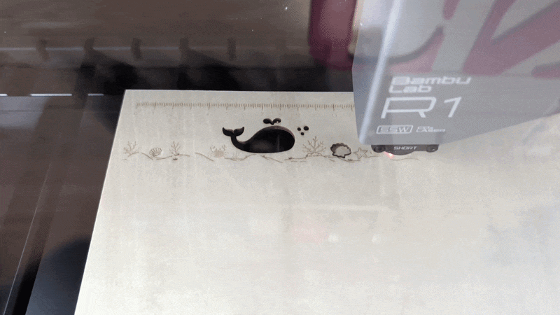 A gif of a laser cutting out a dolphin from wood.