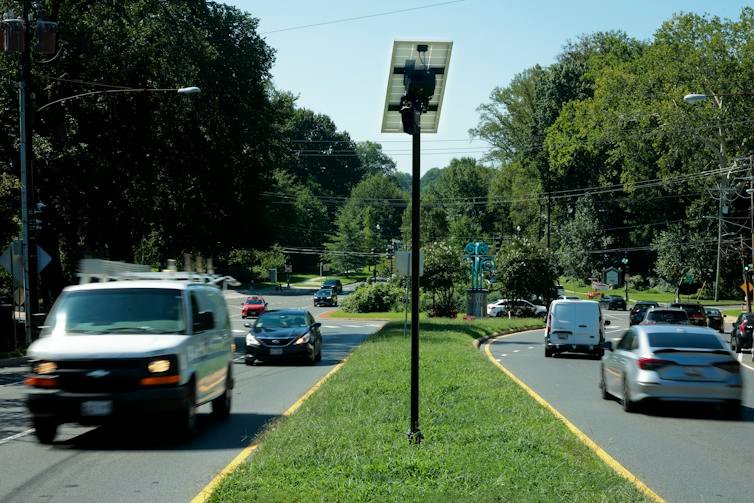 Cars drive by a grass covered median.
