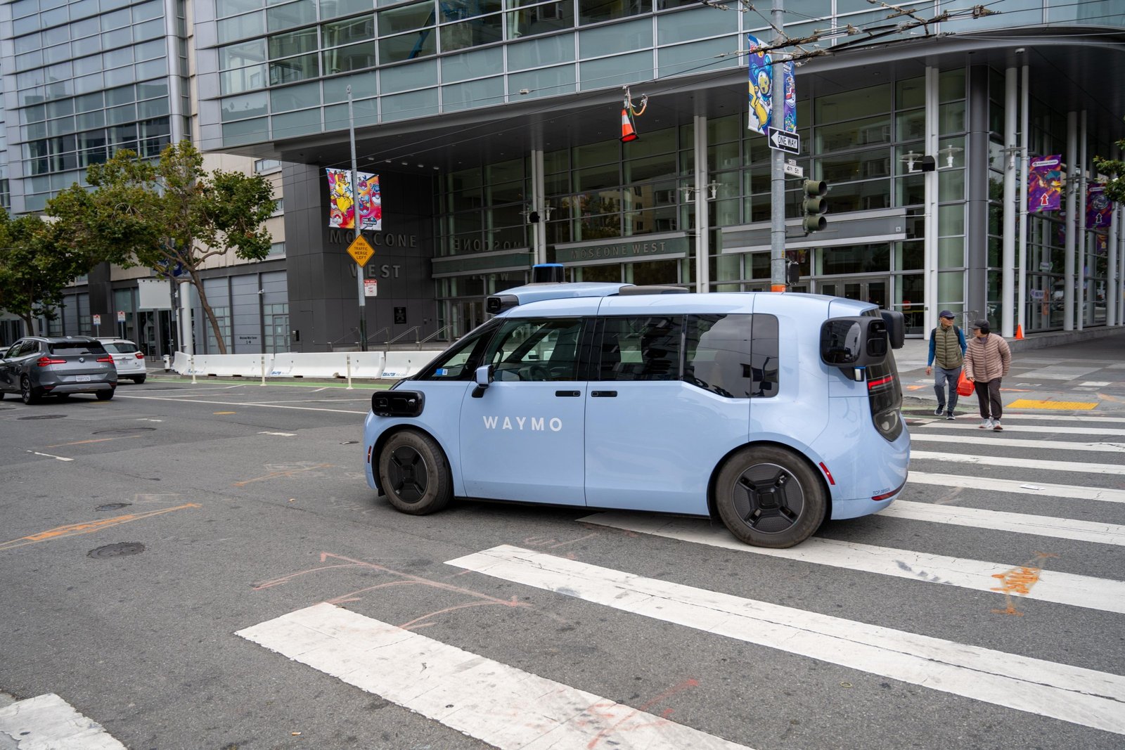 Waymo Ojai autonomous robotaxi travels through the Fourth and Howard streets intersection outside Moscone West, which displays banners for the 2026 Pokemon World Championships, San Francisco, California, August 20, 2026.