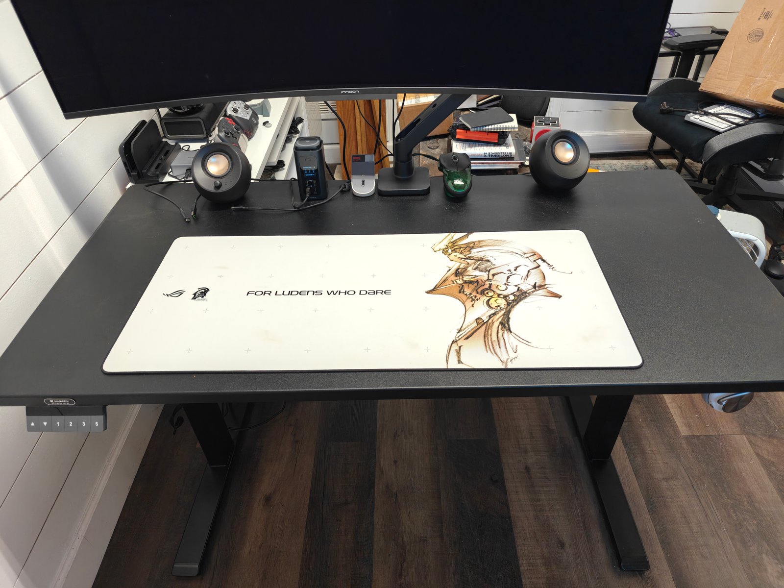 The top of the Boulies MagVida standing dest with a desk mat, monitor and small computer speakers. 