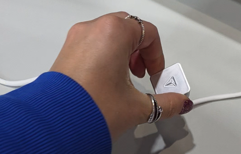 cube shaped, metallic silver pieces that hold the cables in place on the desk. This one has the Secretlab logo on it.