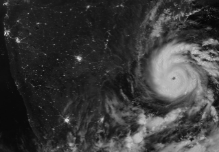A nighttime satellite image shows Arnab's circular structure with bright white clouds as the storm approaches India's east coast. City lights are visible on darkened land surfaces on the left side of the image.