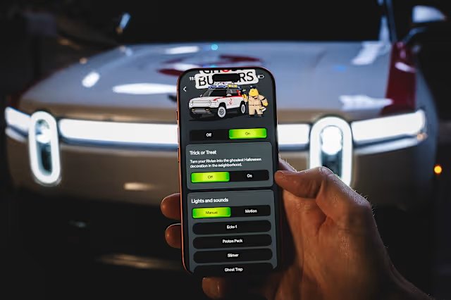 Rivian Ghostbusters app on phone with the Ecto-R1 custom in the background