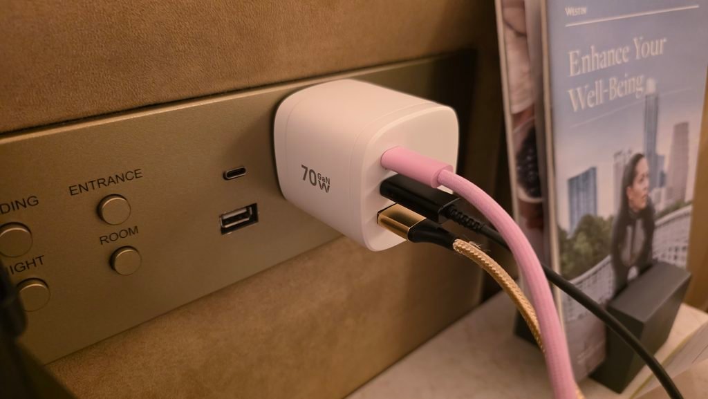 The 70W GaN charger plugged into the wall with two usb-C plugs coming out of it, and one USB-A plug coming out of it.