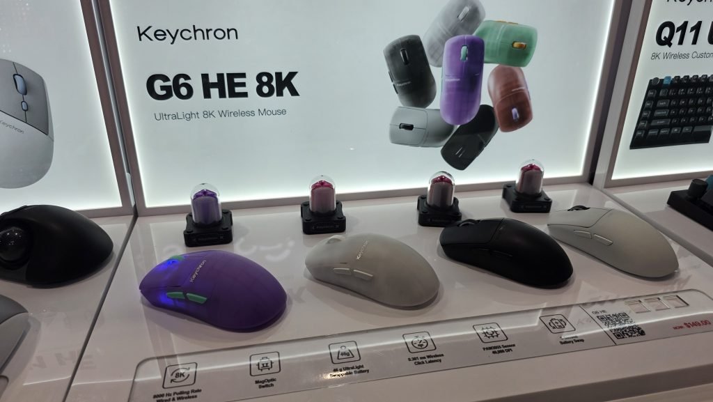 Four G6 HE 8K mice sitting alongside each other in purple transparent, white transparent, black, and grey colourways.