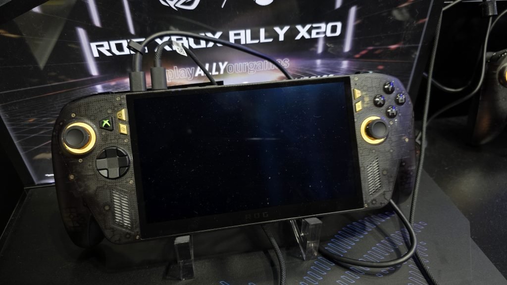 Close up of the Xbox Ally X showing gold highlights around the joysticks, and two gold buttons for the settings and menus keys on each side. The hardware is a translucent black, so you can see the chips and boards of the console.