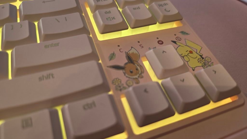 Close up of the arrow keys showing the playing eevee (above the left arrow), and chuckling pikachu (above the right arrow). There are a couple of leaves and flowers to round out this section of the keyboard.