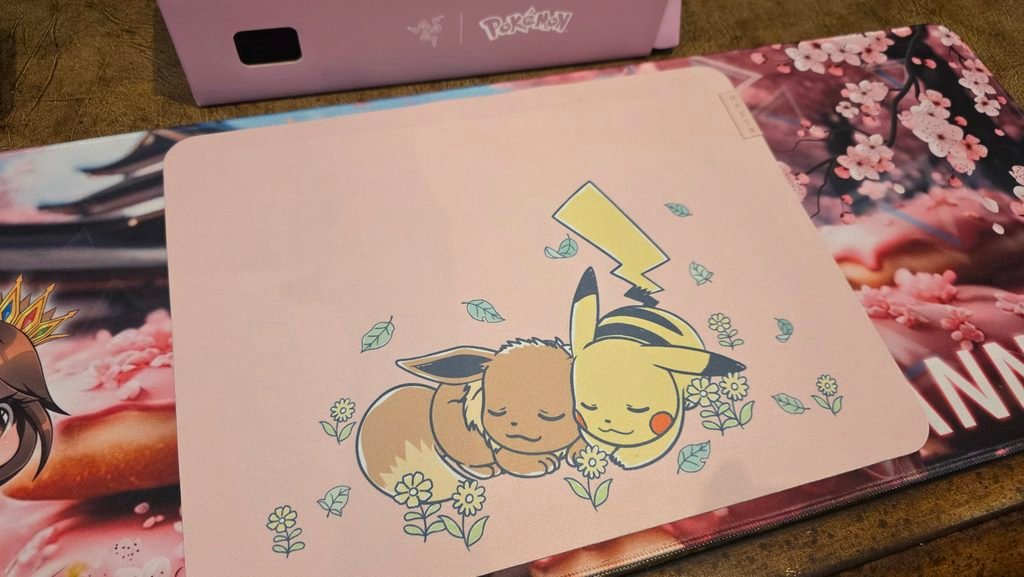 Razer mousemat showing the sleeping Pokemon Pikachu and Eevee graphic with the spring flowers around the pair. The background of the mat is the same soft pink as the rest of the collection.