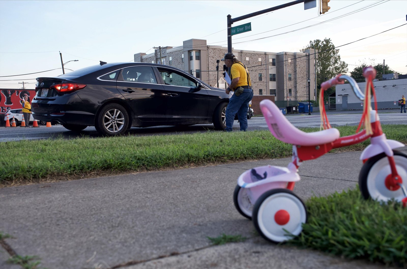 An HCAG member is speaking with a local motorist about signing the Flock petition. A pink child’s tricycle is in the foreground.
