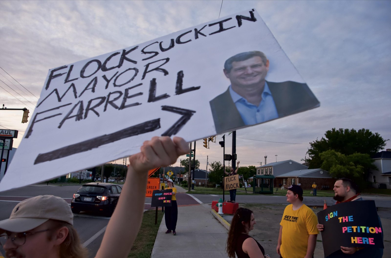 HCAG member holding sign, “Flock Suckin Mayor Farrell” in the foreground.