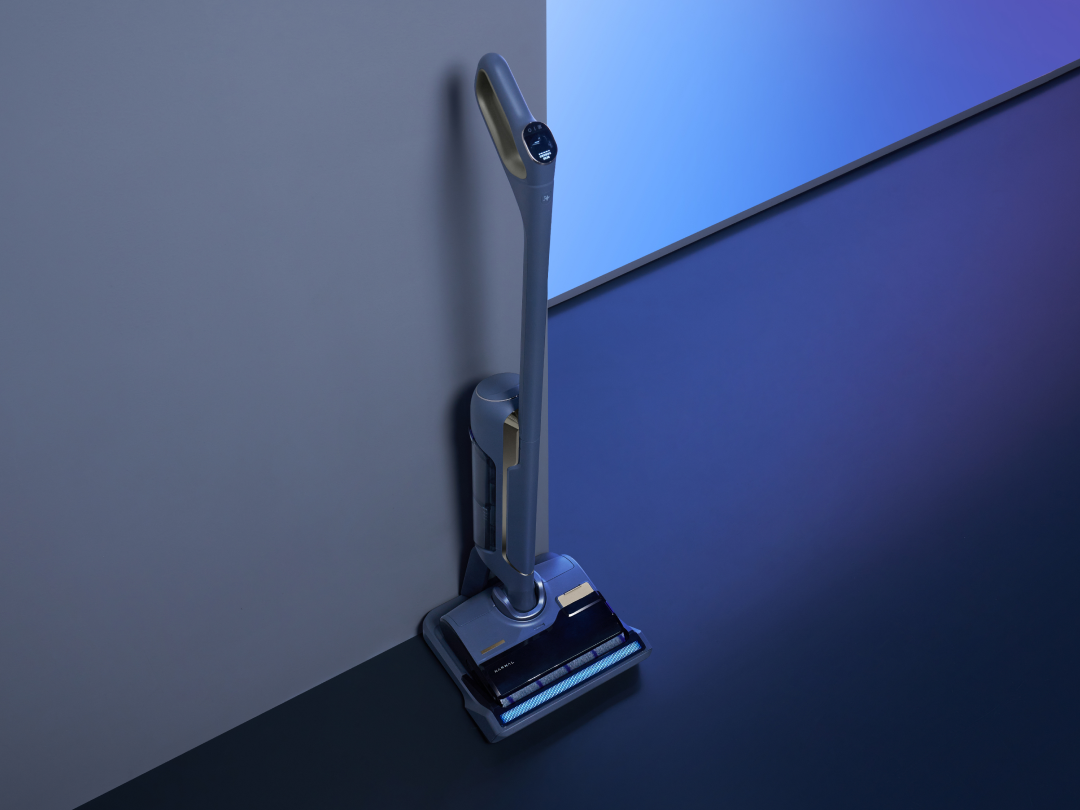 A cordless vacuum leaning against a gray wall.