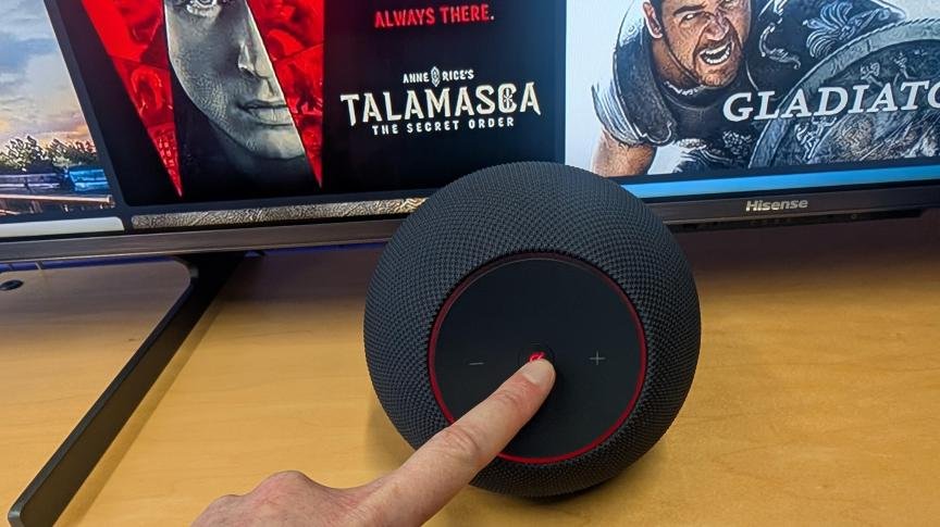 Finger touching Amazon Echo Studio device.
