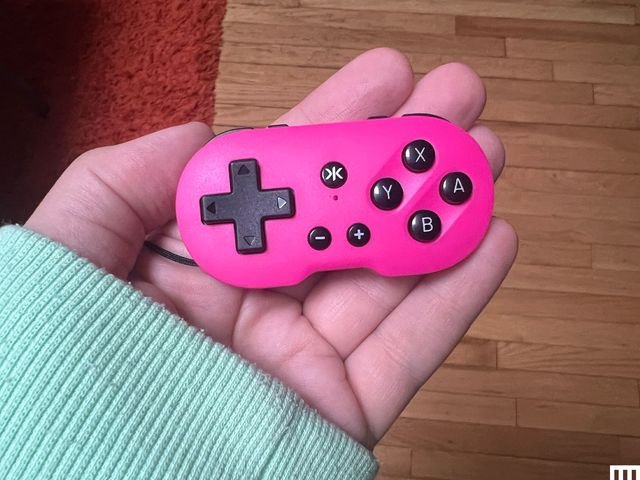 Crkd Atom Controller, a tiny pink video game controller in the palm of someone's hand