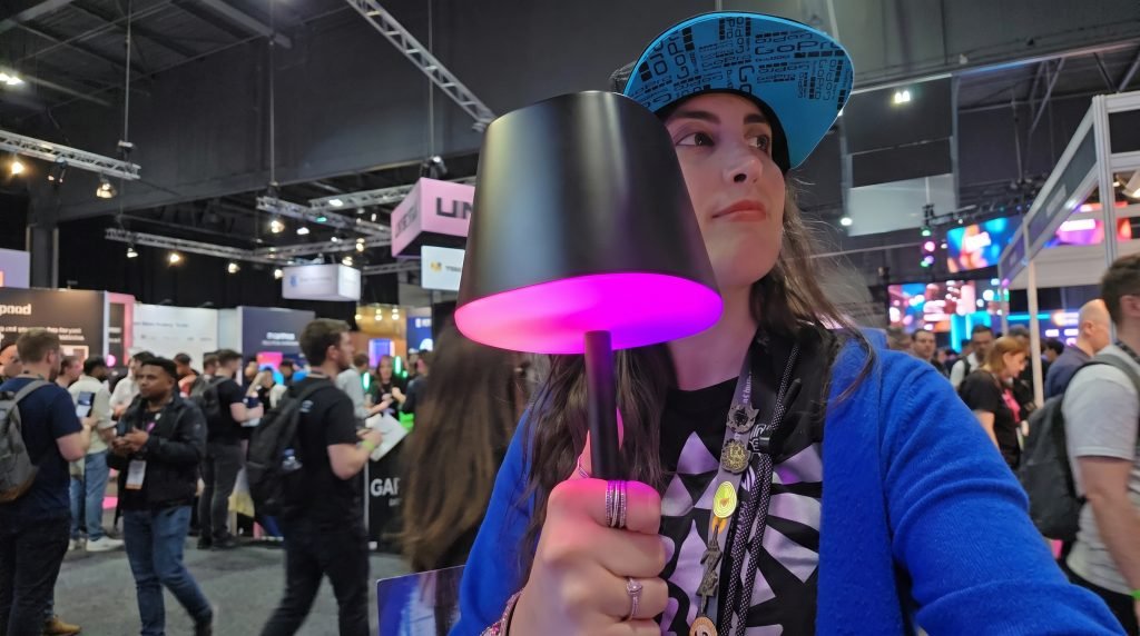 Me walking around the expo hall carrying the lamp in my hand. It looks like a stand desk lamp (traditional), black, and has some RGB around the rim of the lamp shade.