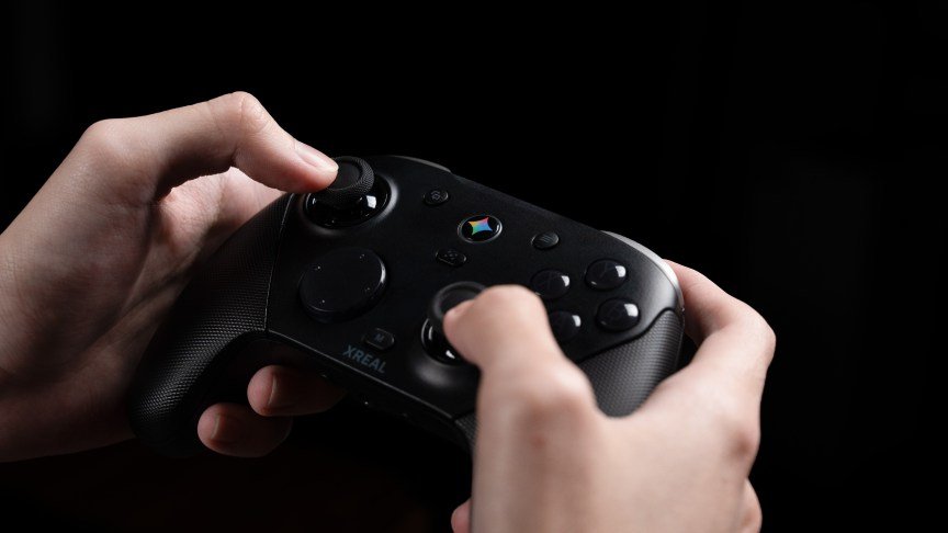 Two hands hold a black game controller that has a Gemini button in the center.