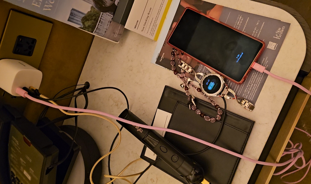 The power outlet shows a phone, smart watch, and hair straightener plugged into the same GaN power brick.