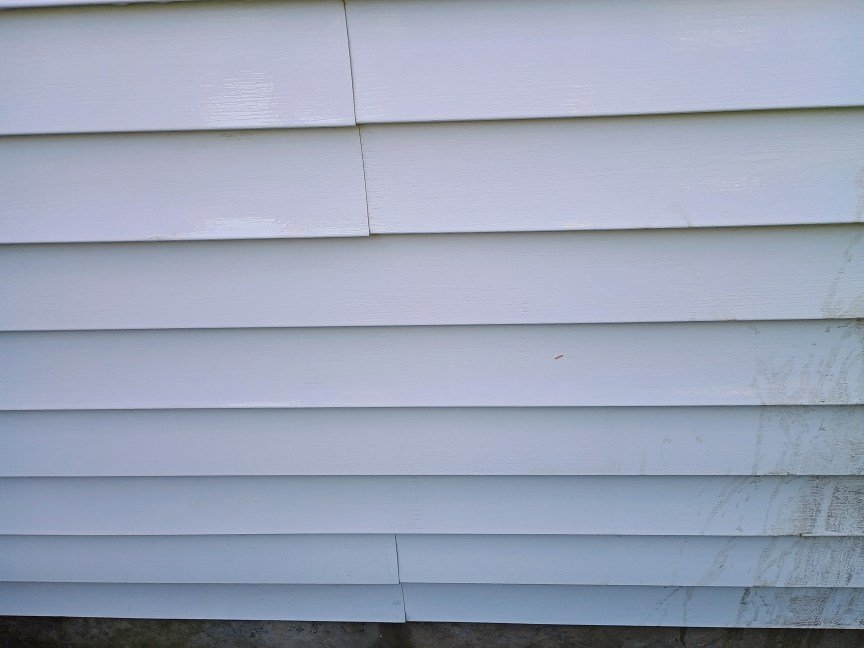 A view of house siding after it was cleaned with a LawnMaster pressure washer. The result looks very clean.