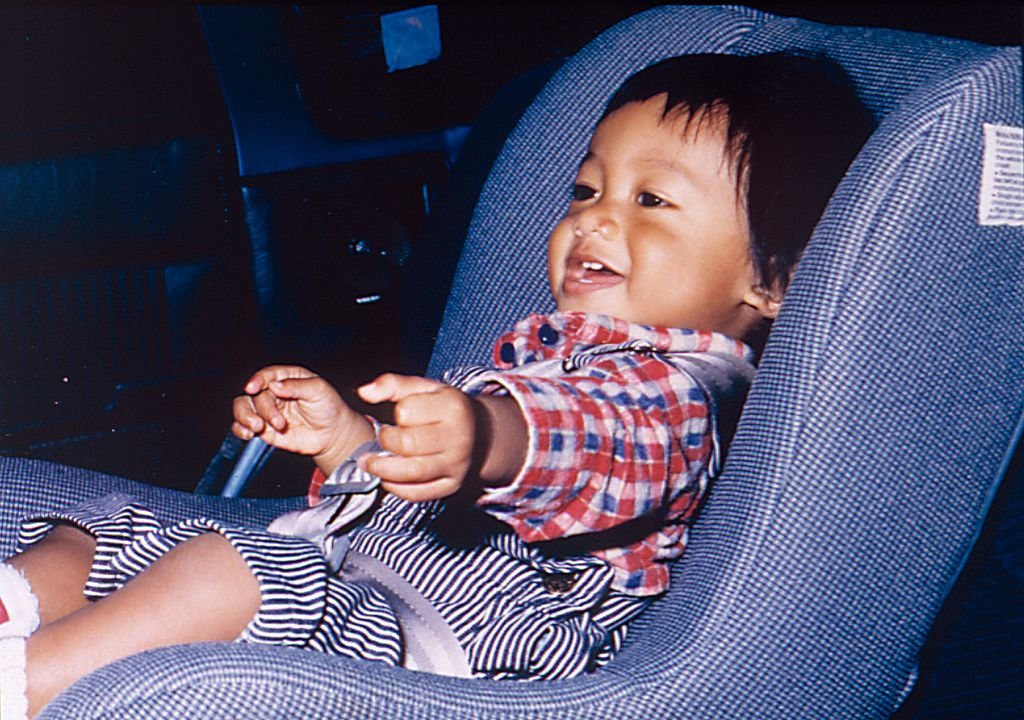 Asian baby in vintage car seat.
